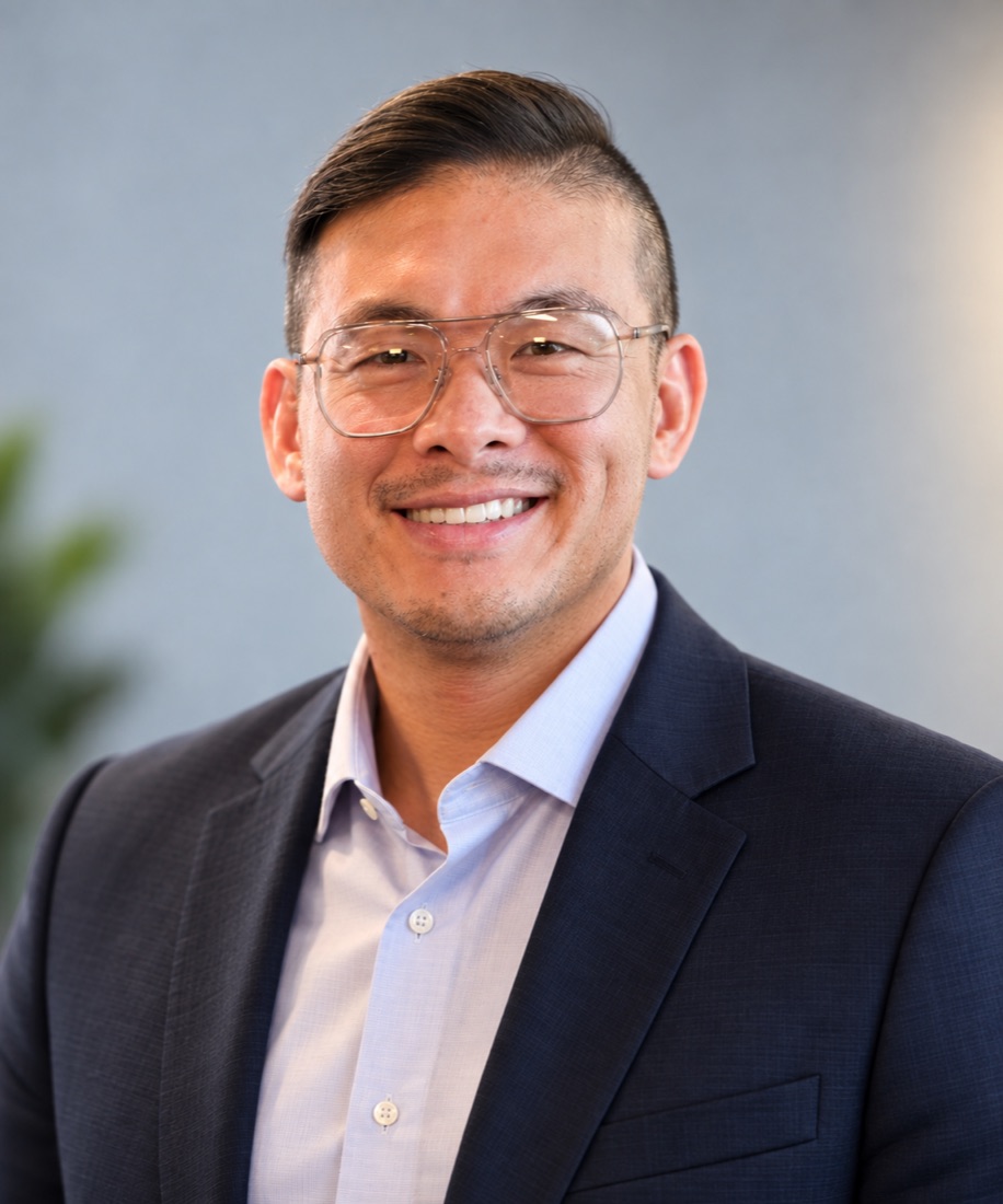 Jason Wong smiling in a navy blazer and light blue shirt, in an office