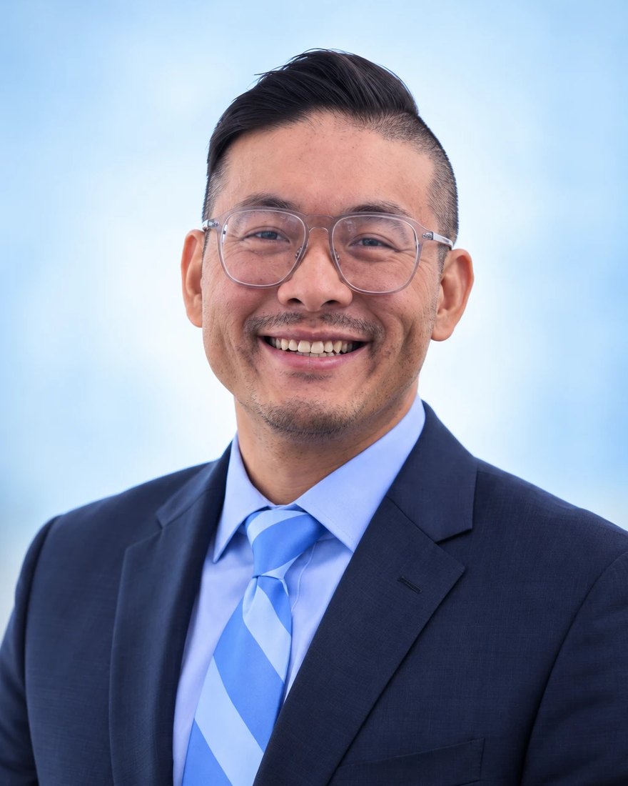 Headshot of Jason Wong smiling, in a navy suit and light blue striped tie